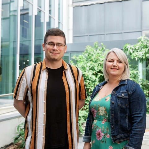 A male and a female postgraduate student smiling at the camera 