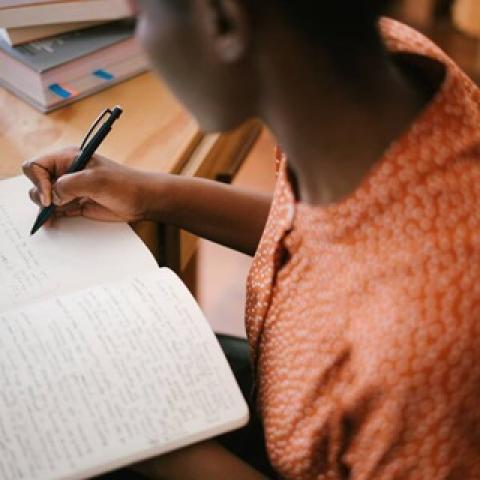 A woman sitting at a desk writing in a notebook