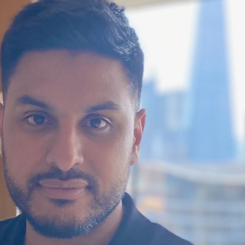 A headshot of Abbas Kanani looking to the camera wearing black polo shirt