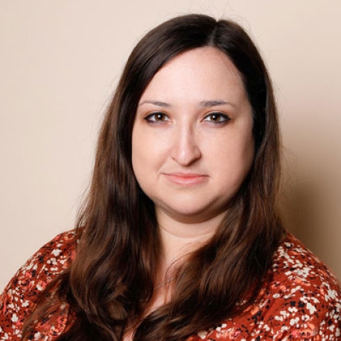 Headshot of Alice Hendy MBE smiling to camera wearing orange dress