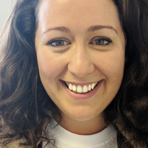 Becca Dean smiling to camera wearing aviator jacket and white top