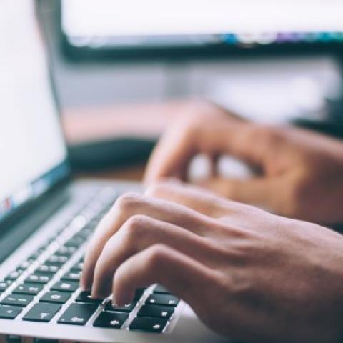 Hands typing on a laptop