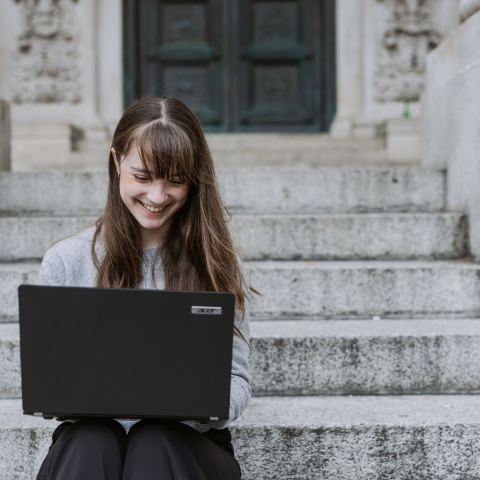 Person sitting on stone steps with a laptop.