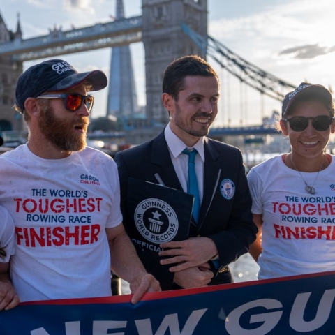 Two rowers and a Guinness World Record adjudicator in front of Tower Bridge, London,