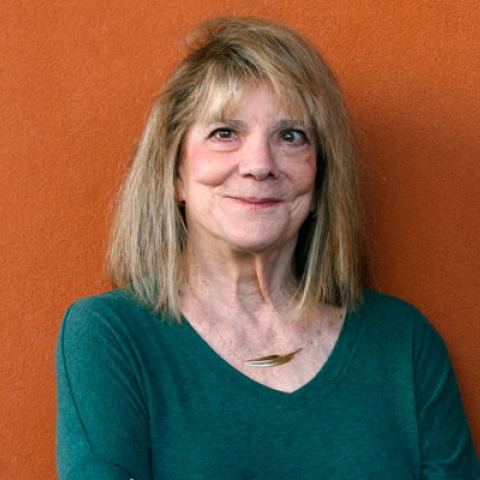 Headshot of Elizabeth Loftus wearing green jumper with necklace smiling to camera