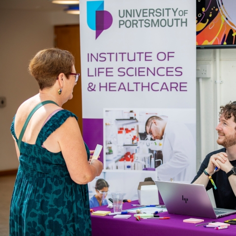 A person standing by a stand at the Festival of Doctoral Research 2026