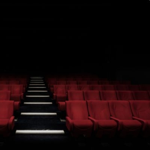 An empty cinema screening room with rows and rows of red seats
