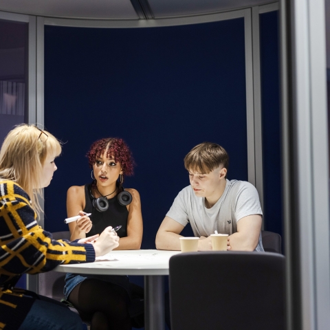 Young adults sat around an office table having a conversation