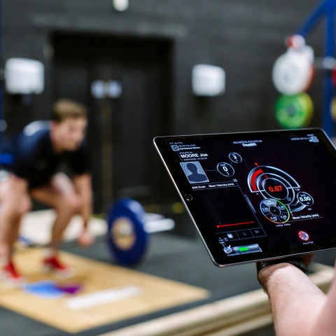 A student tracking an athlete's progress in the gym