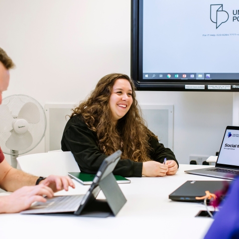 Smiling professional communication student seated at table