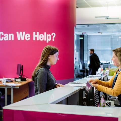 Female student standing at careers and employability help desk