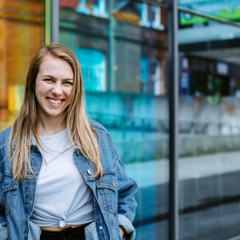 Student wearing blue jean jacket and smiling.