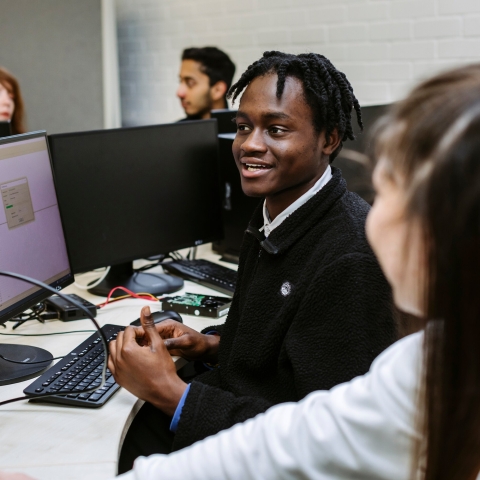 A male and female student working on computers