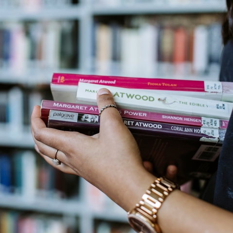 Close up of hands holding a pile of books