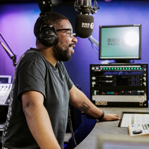 Alumnus Nels Hylton behind a microphone in the studio at BBC Radio One