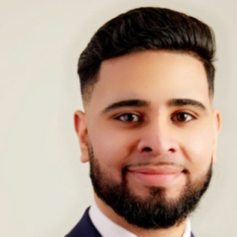Headshot of Haris Kiani smiling to camera with beard wearing suit