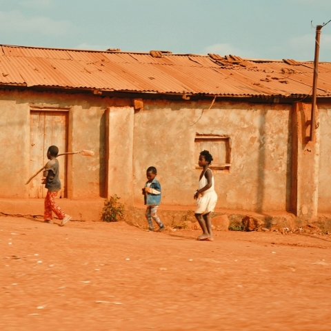 Image of housing in rural Nigeria with three children playing in front of a dwelling
