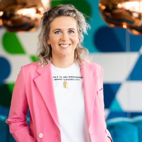 Headshot of Laura May Coope smiling to camera in pink blazer and white tshirt