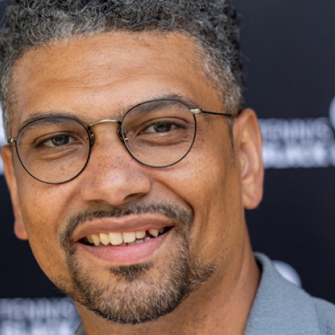 Leon Mann smiling to camera wearing glasses