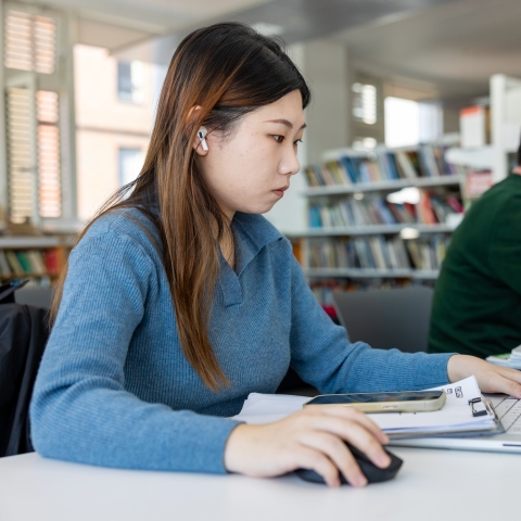 Female student with long hair in the library on a computer