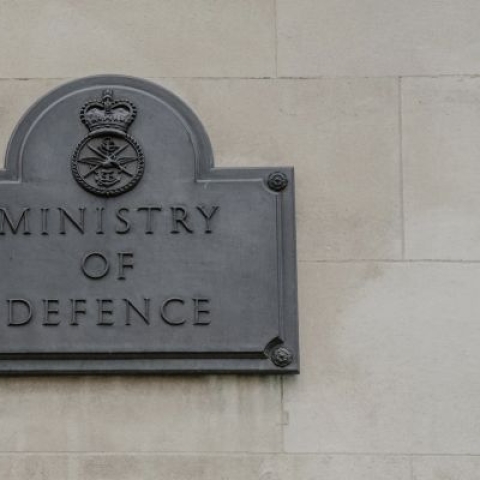A picture of a grey sign on a building saying the words 'Ministry of Defence' 