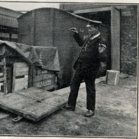 Image of a railway work on a station platform next to a goods crate with its side open and lying on the platform