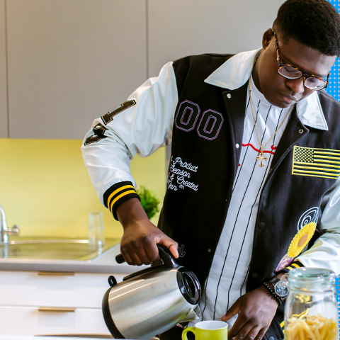 Student pouring tea in university student accommodation kitchen
