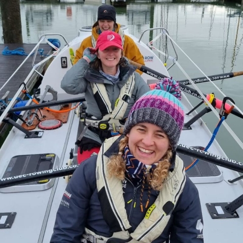 Three female rowers on their rowing boat ready to leave the harbour