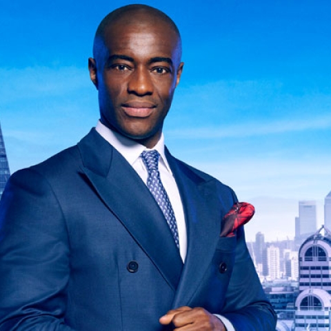 Headshot of Tim Campbell MBE looking to camera wearing blue suit with London backdrop