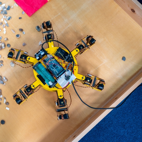 Image of yellow spider-like robot organising rocks