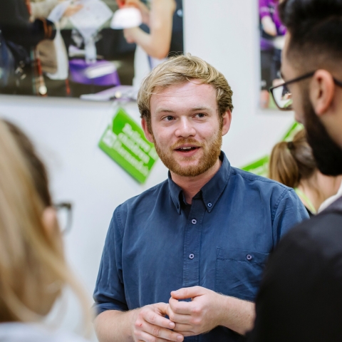 member of staff talking to two people at volunteering fair