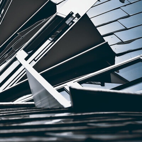 Ground angle view of a tall building with sinuous architecture, jutting windows and glossy exterior panels