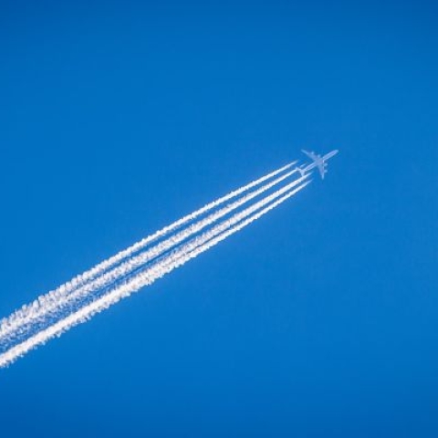 A jet against a blue sky with contrail