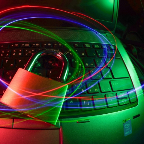 Image of a laptop computer keyboard with some swirls of light floating above and in the centre of that is a metal padlock