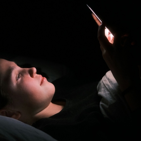 Young person in bed on their mobile phone