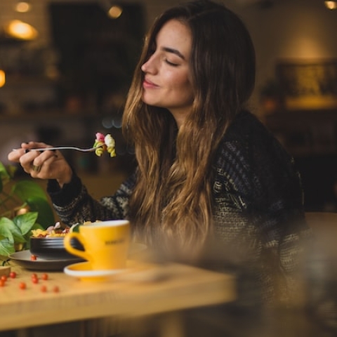 Woman smelling her dinner as she eats