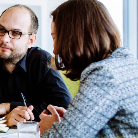 Male staff member facing two female staff members in meeting