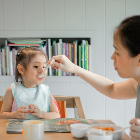 child being fed with a spoon at table