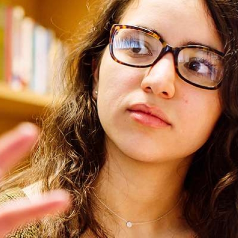 Female student in glasses listening attentively to someone speaking