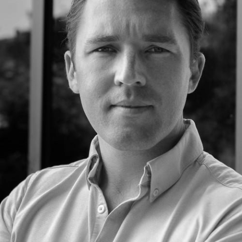 Olly Shepherd smiling to camera wearing suit in black and white image