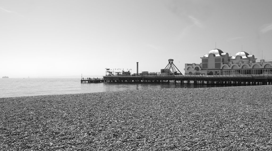 black and white photo of a pier by the beach