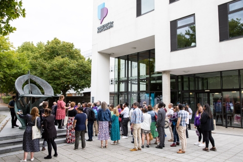 Photo of attendees gathered outside the Dennis Sciama CafeAlumni Weekend