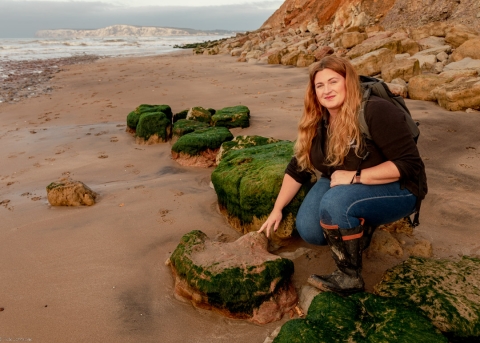 Megan crouched down touching a rock on the Isle of Wight