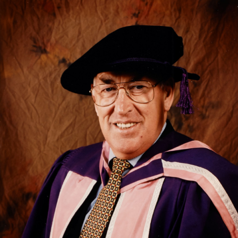 Sir Anthony Cleaver smiling at camera wearing graduation gown and cap