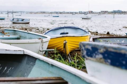 a group of colourful rowing boats sitting on the shore with the sea in the background
