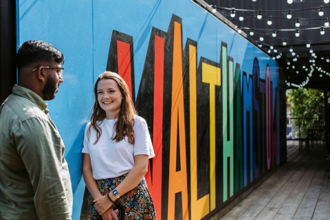 Male and female student in front of wall