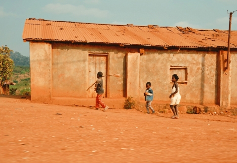 Image of housing in rural Nigeria with three children playing in front of a dwelling