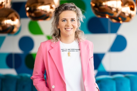 Headshot of Laura May Coope smiling to camera in pink blazer and white tshirt