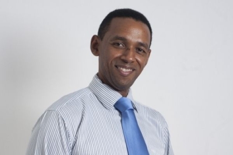 Melwyn Madelon smiling at camera wearing suit