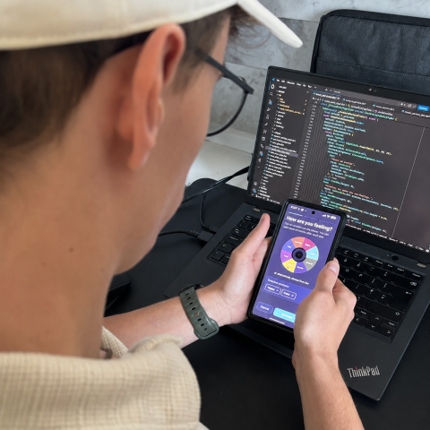 Over the shoulder of a male student opening the Reverie app with a screen showing "How are you feeling?"